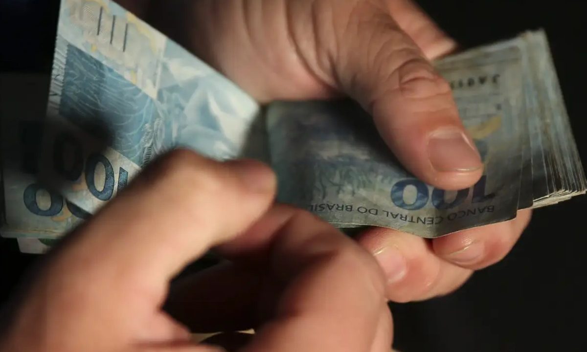 Homem segurando dinheiro para representar prêmio da Lotofácil 3674