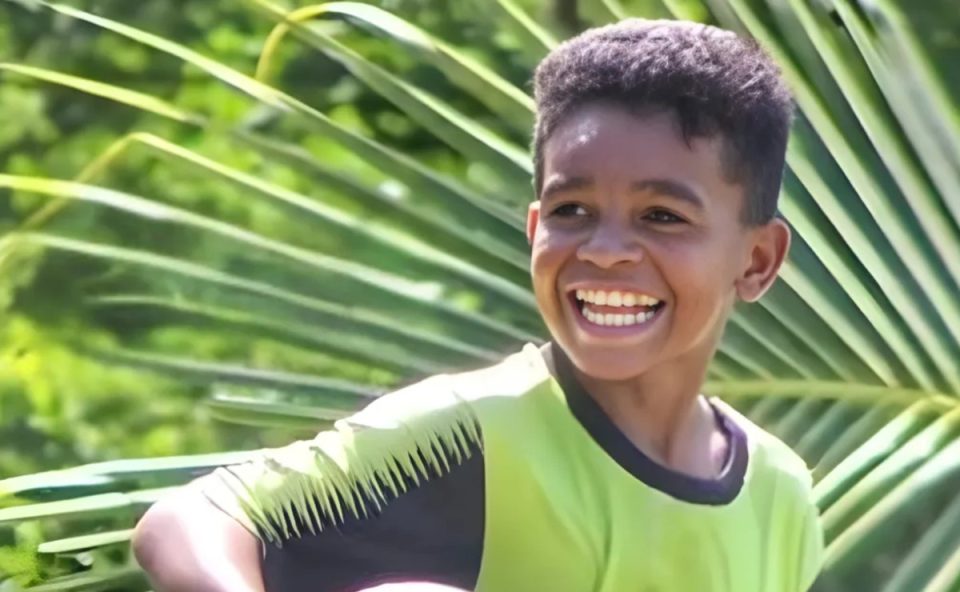 Foto mostra menino negro sorrindo, enquanto veste uniforme de futebol e segura uma bola. O menino, de 13 anos, foi morto com um tiro no rosto ao entrar em uma casa para buscar pipa, no Maranhão.
