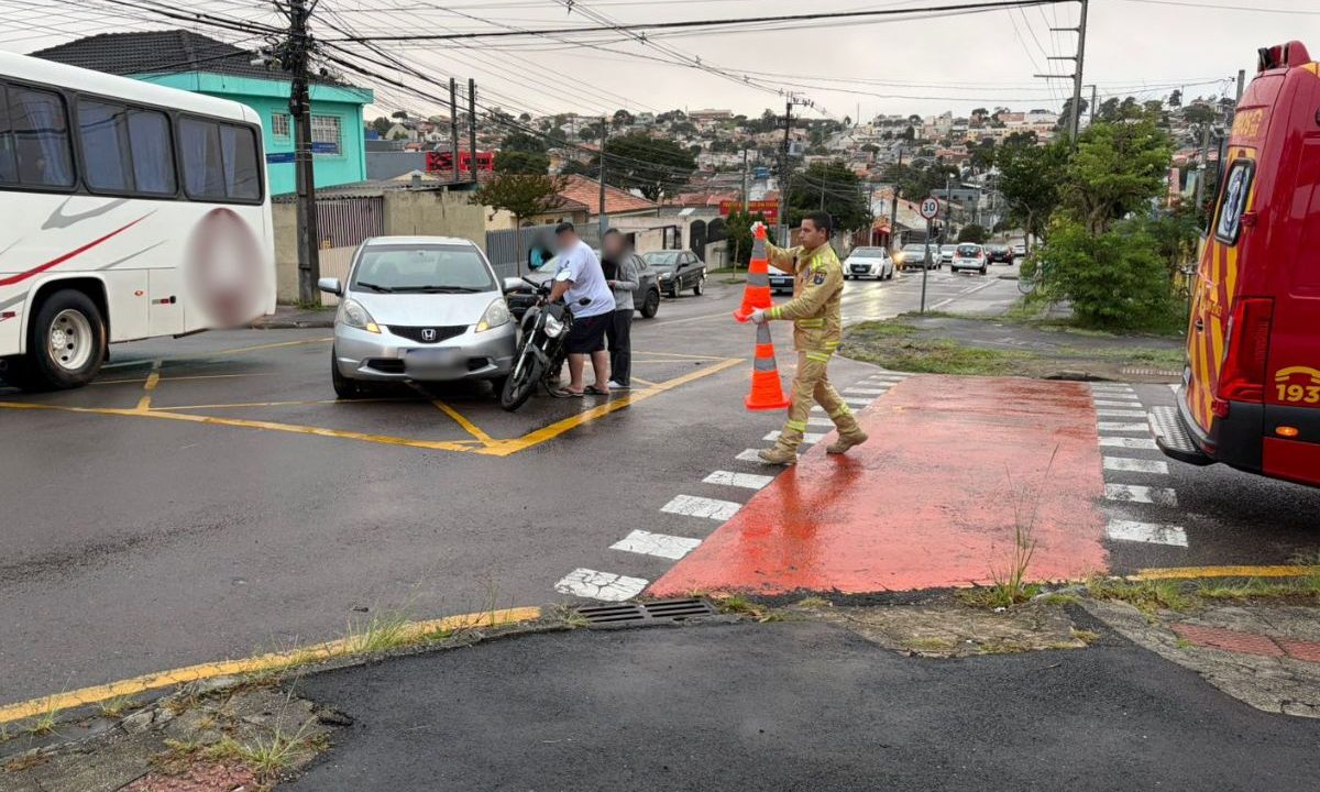 foto do acidente com carro que deixou o motociclista ferido em curitiba. na imagem aparece duas pessoas empurrando a moto, o carro envolvido na batida e a ambulância do siate