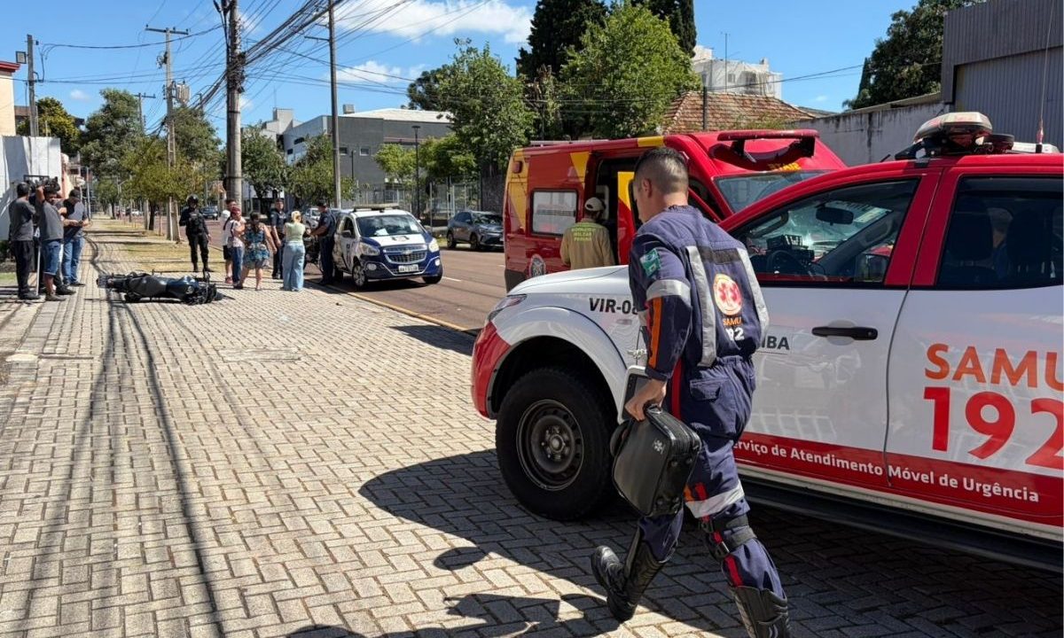 Motociclista fica gravemente ferido após colisão com carro no bairro Rebouças, em Curitiba. A foto mostra imagens do acidente: a moto caída no chão, pessoas do acidente e profissionais do Samu e do Siate atuando no resgate.