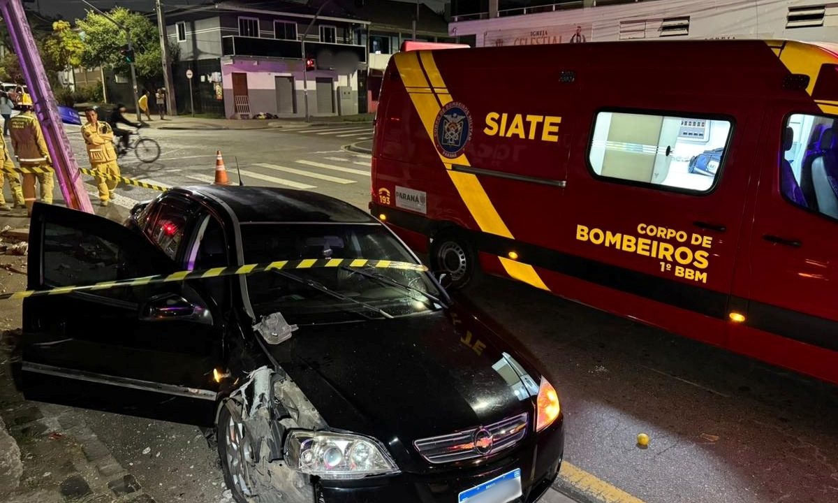 Foto mostra carro preto parado próximo a poste destruído depois de batida em cruzamento do bairro Prado Velho, em Curitiba
