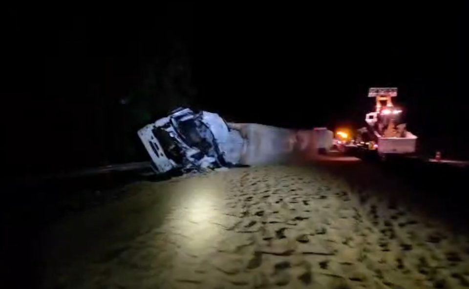 Foto mostra um dos caminhões envolvidos no acidente da BR-277, em Morretes, tombado às margens da rodovia, sobre uma carga derramada de milho. Motorista morreu na batida entre os caminhões.