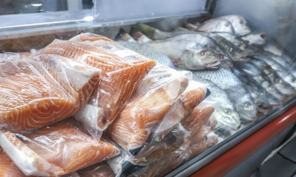 Filés de salmão embalados expostos em vitrine refrigerada ao lado de peixes inteiros para serem vendidos na sexta-feira santa em curitiba
