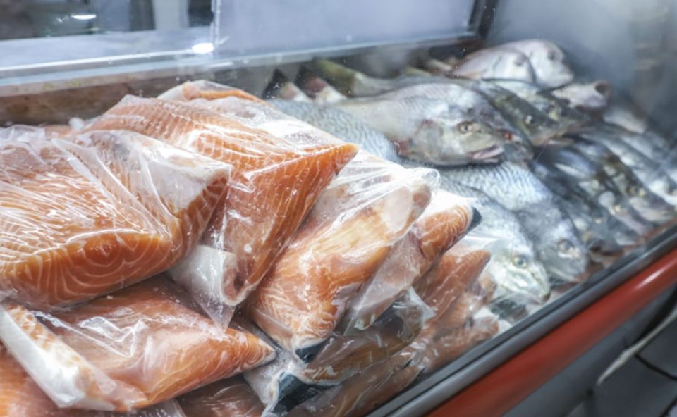 Filés de salmão embalados expostos em vitrine refrigerada ao lado de peixes inteiros para serem vendidos na sexta-feira santa em curitiba