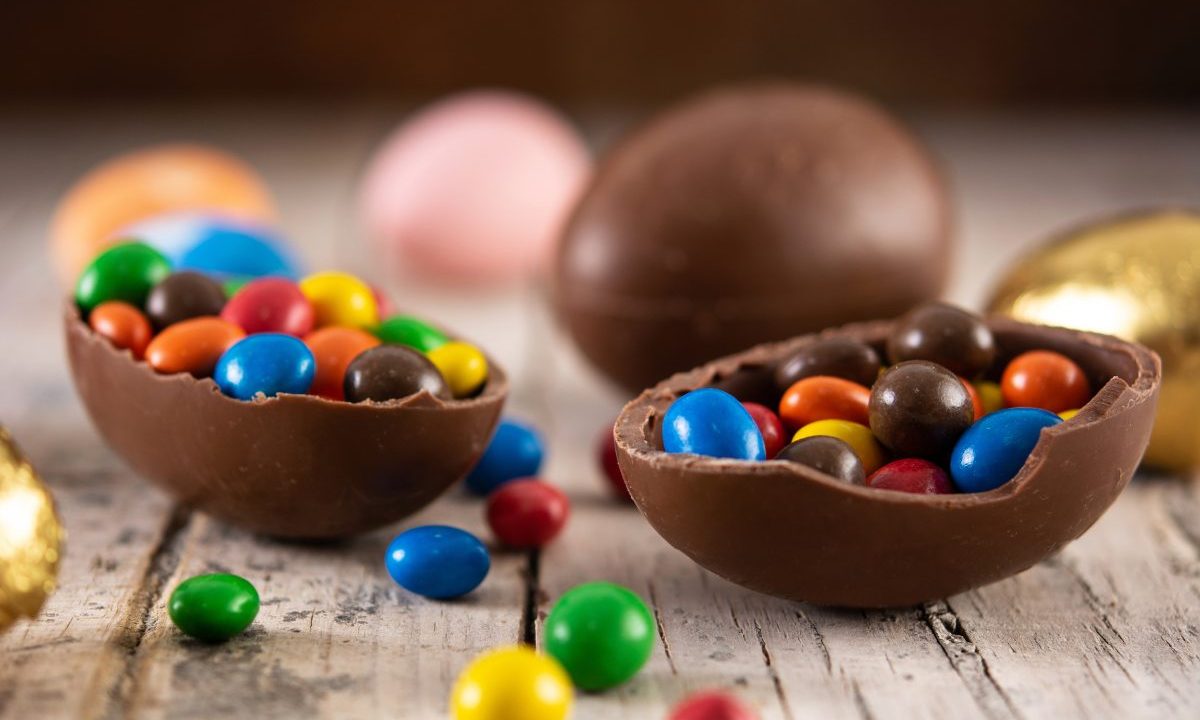 Imagem ilustrativa mostra um ovo de páscoa cheio de confetes. O ovo é marrom, de chocolate. Os confetes são coloridos. A ideia é ilustrar a páscoa em curitiba.
