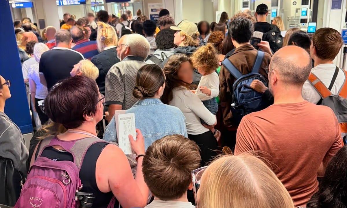 Foto de passageiros presos em aeroporto. Eles estão desorganizados e espaçados, sem uma fila definida.