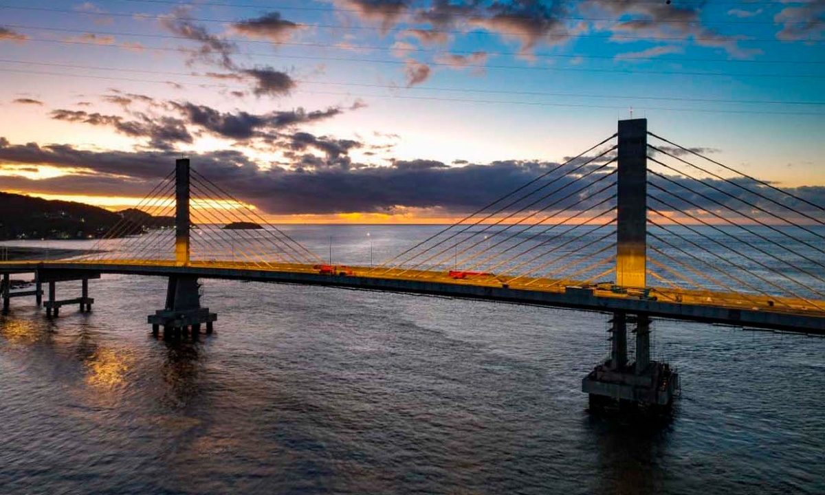 Foto da Ponte de Guaratuba iluminada, na etapa final da obra no litoral do Paraná.