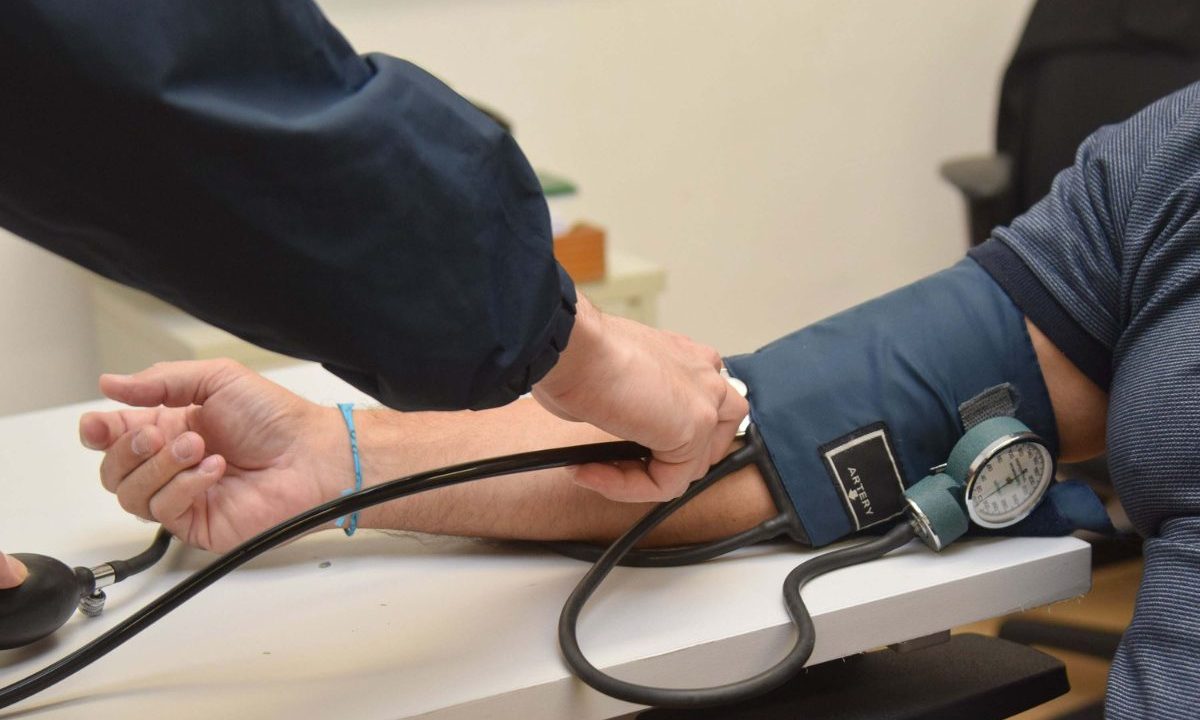 Profissional de saúde mede a pressão arterial de um paciente com aparelho manual no braço