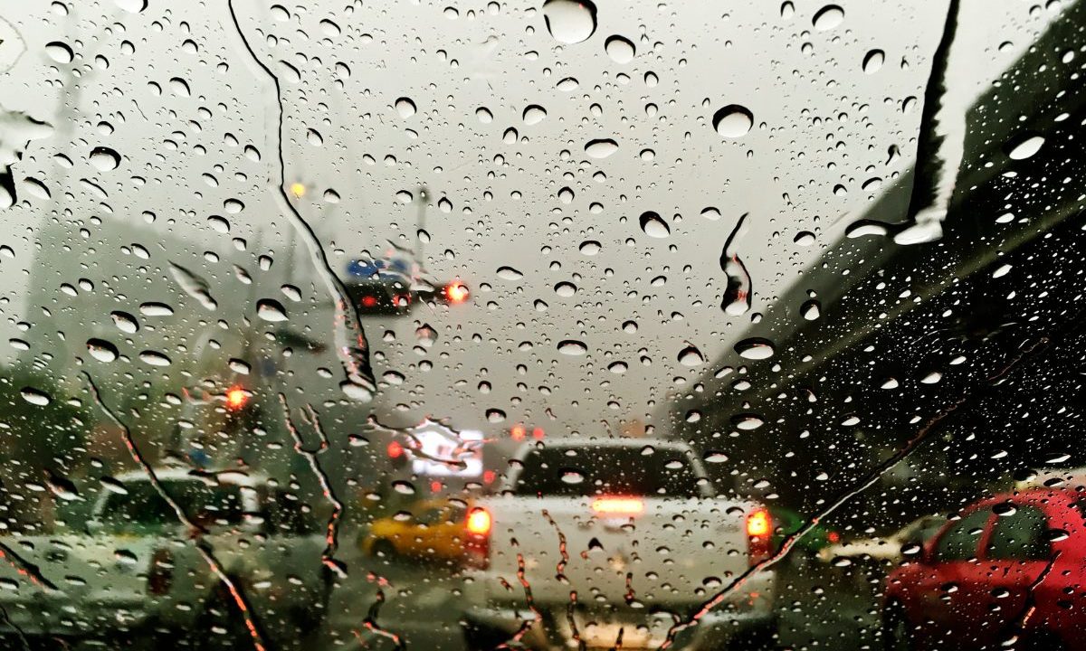 Imagem ilustrativa para previsão do tempo em Curitiba nesta quarta-feira. Imagem mostra um vidro molhado no trânsito. Há carros na frente e um semáforo vermelho.