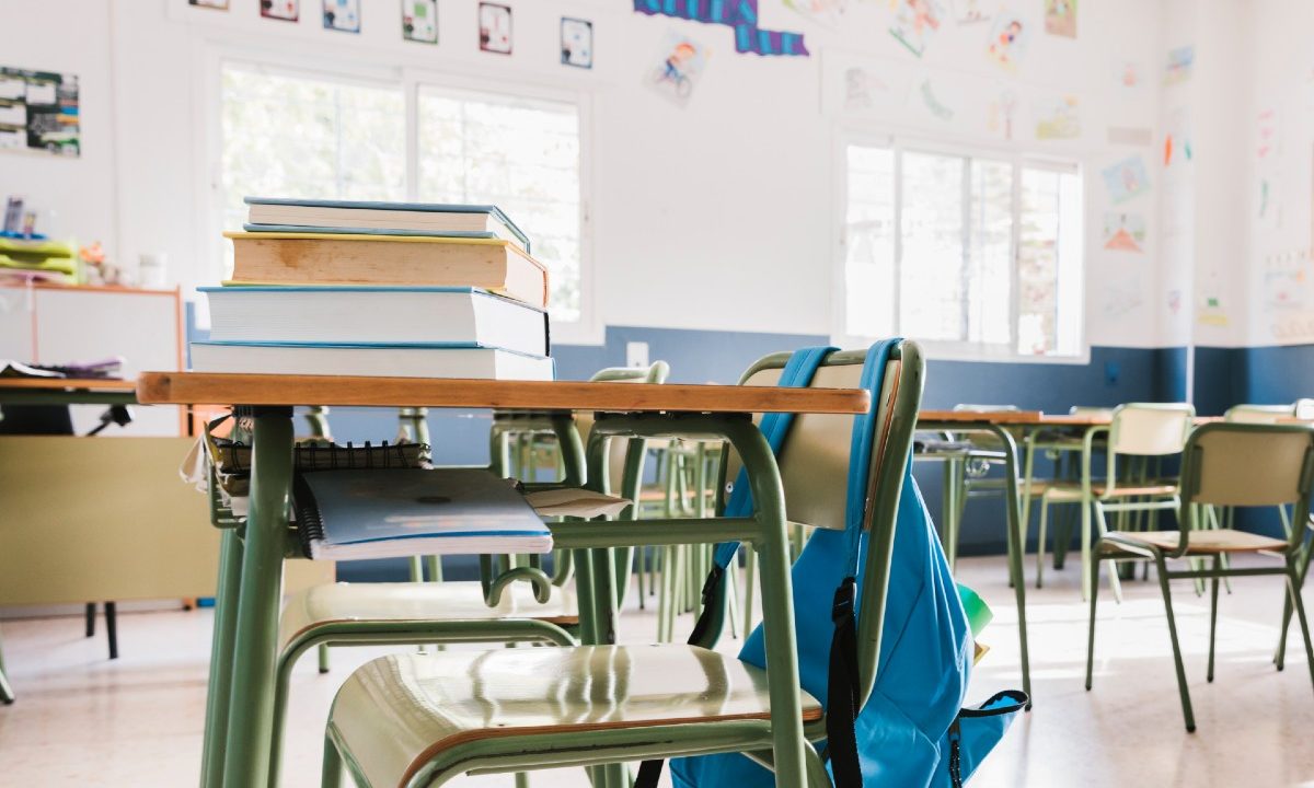Mesa, cadeira, livros e mochila em uma sala de aula, ilustrando o caso da professora substituta presa nos Estados Unidos.