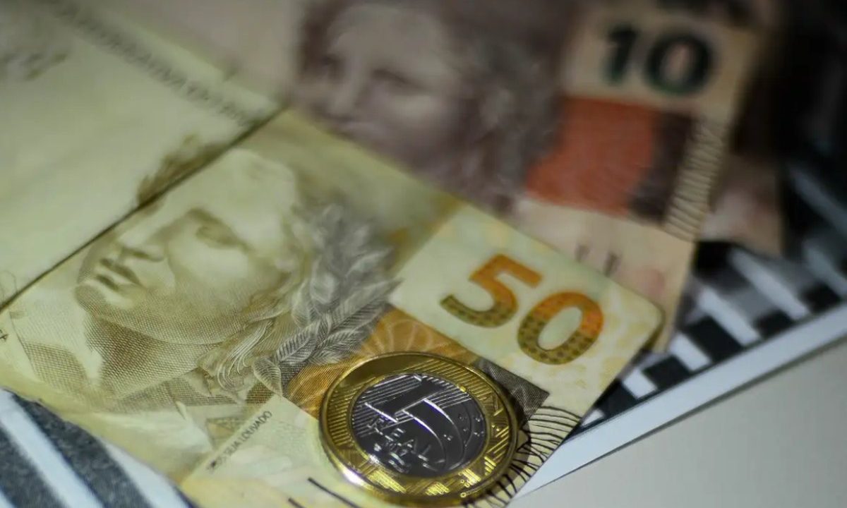 Foto de cédulas de reais e moeda em cima de uma mesa; imagem usada para ilustrar dinheiro que será recebido pelo ganhador no resultado da Loteria Federal 6054