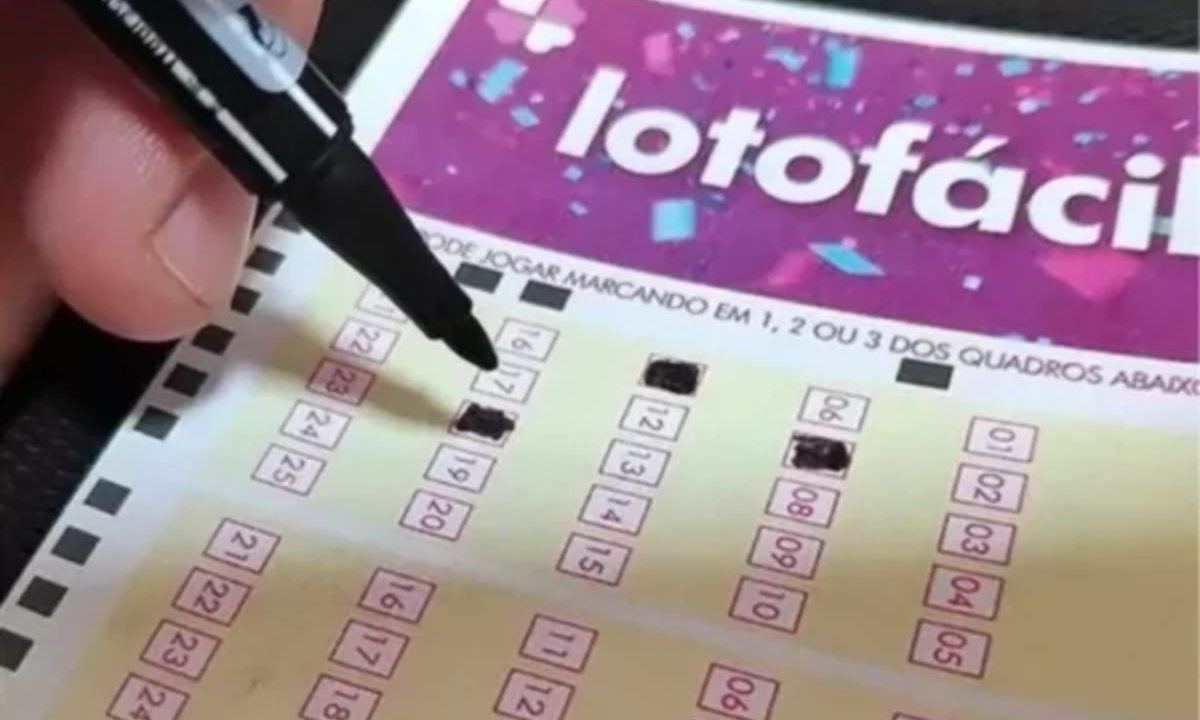 Mão preenchendo volante da Lotofácil 3669