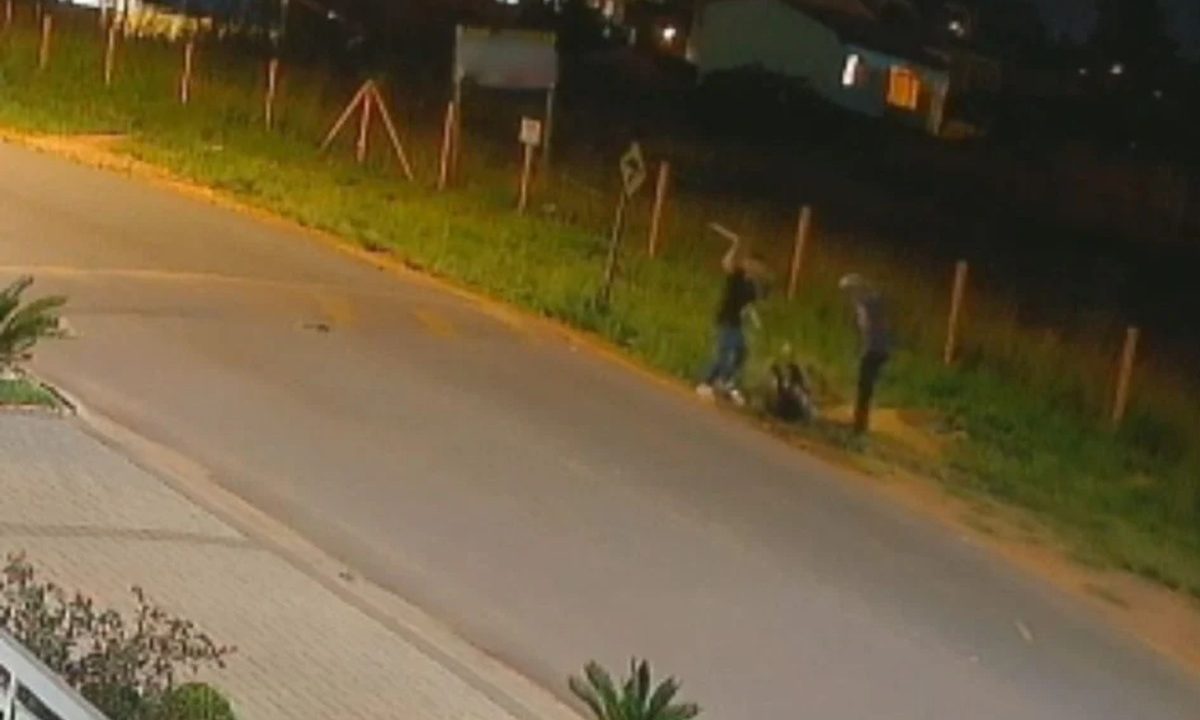 Foto registrada por câmera de segurança durante a noite mostra dois homens espancando um homem com um facão e chutes em uma rua de Fazenda Rio Grande. Vítima continua em estado grave.