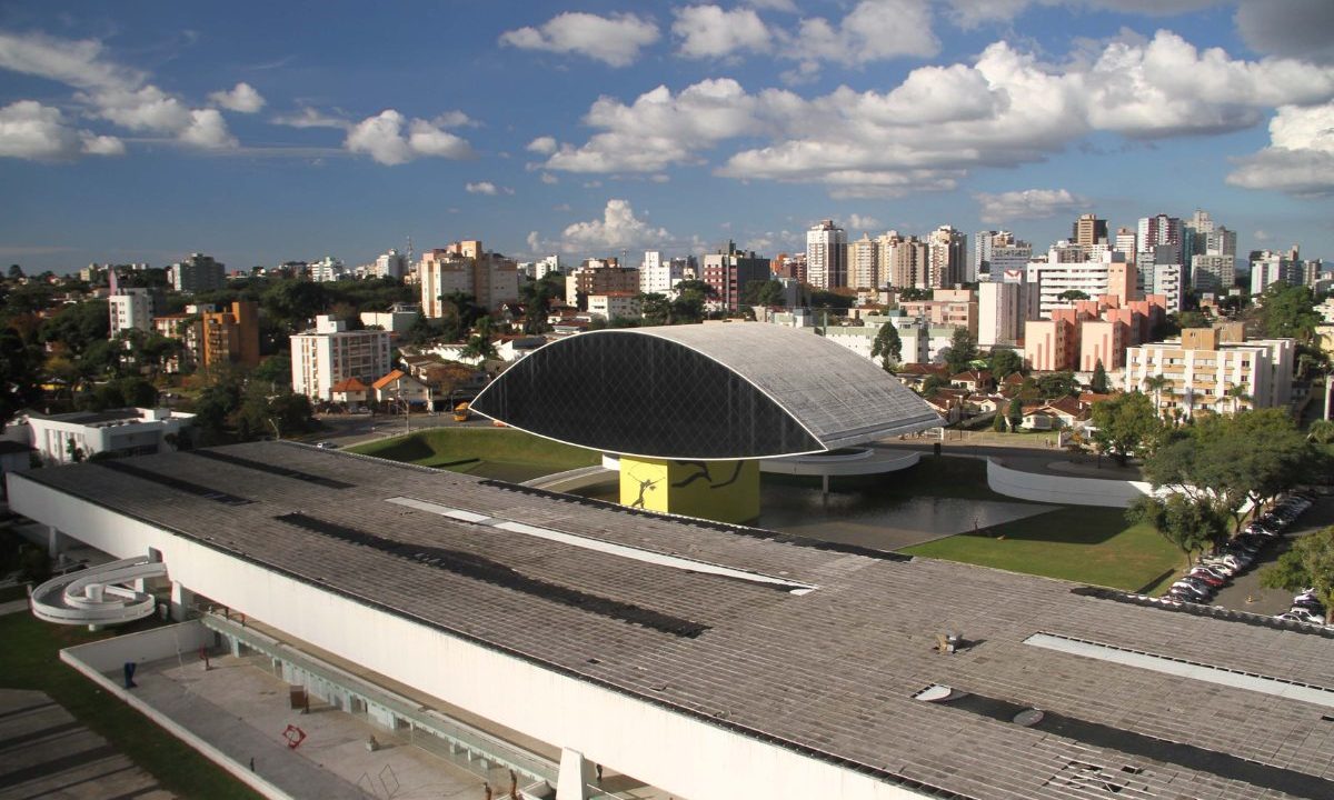 Imagem ilustrativa para o tempo em Curitiba nesta quinta-feira. Imagem mostra o MON, o dia está com céu aberto e sol.