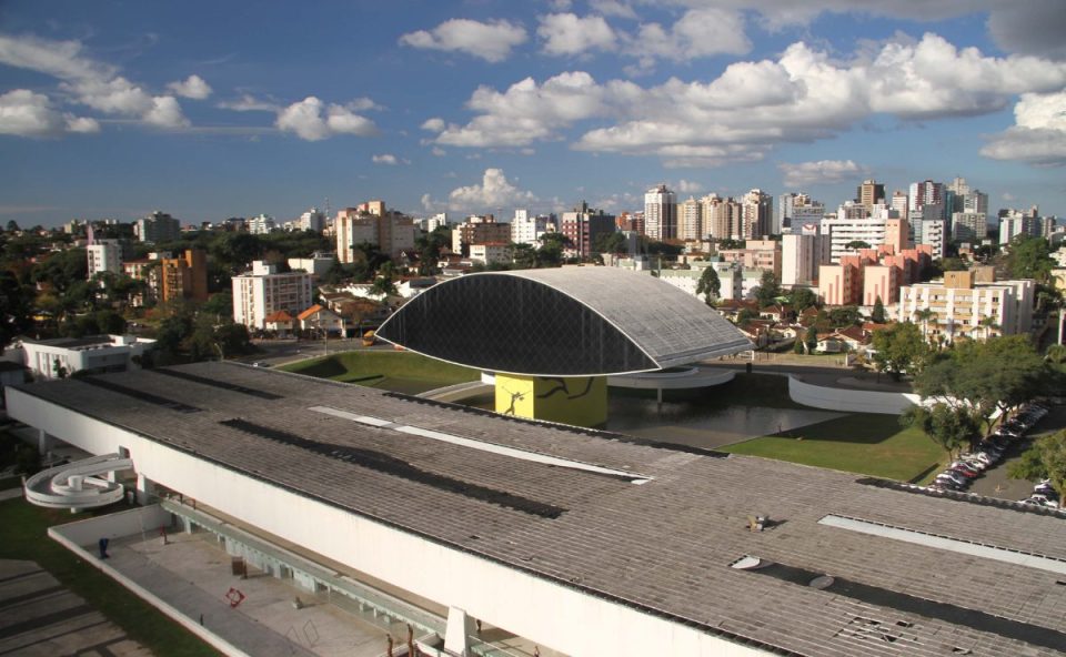 Imagem ilustrativa para o tempo em Curitiba nesta quinta-feira. Imagem mostra o MON, o dia está com céu aberto e sol.
