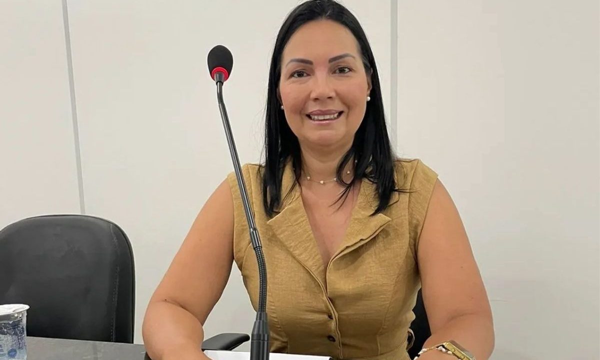 Vereadora de Matinhos Hirman da Saúde sentada em bancada com microfone, investigada em esquema de rachadinha.