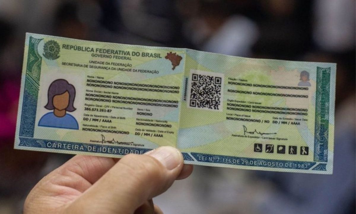 Modelo do novo RG (Carteira de Identidade Nacional) sendo segurado por uma mão, exibindo o layout com QR Code e informações de segurança.