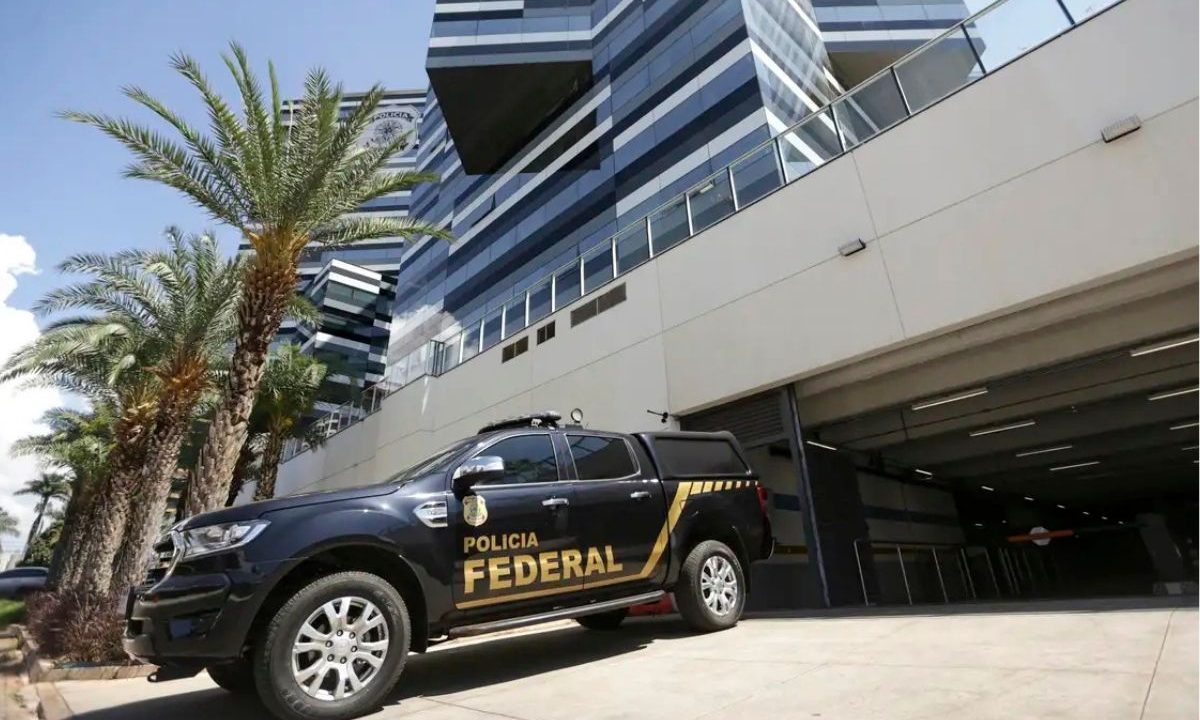 Viatura preta da Polícia Federal estacionada em frente a um edifício moderno de arquitetura espelhada, ilustrando a operação contra fraude no INSS.