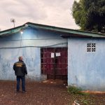 Agênte parado em frente a uma casa cumprinco operação da PF contra exploração sexual