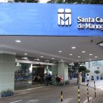 Fachada da Santa Casa de Maringá com entrada de pacientes e visitantes na área externa do hospital.