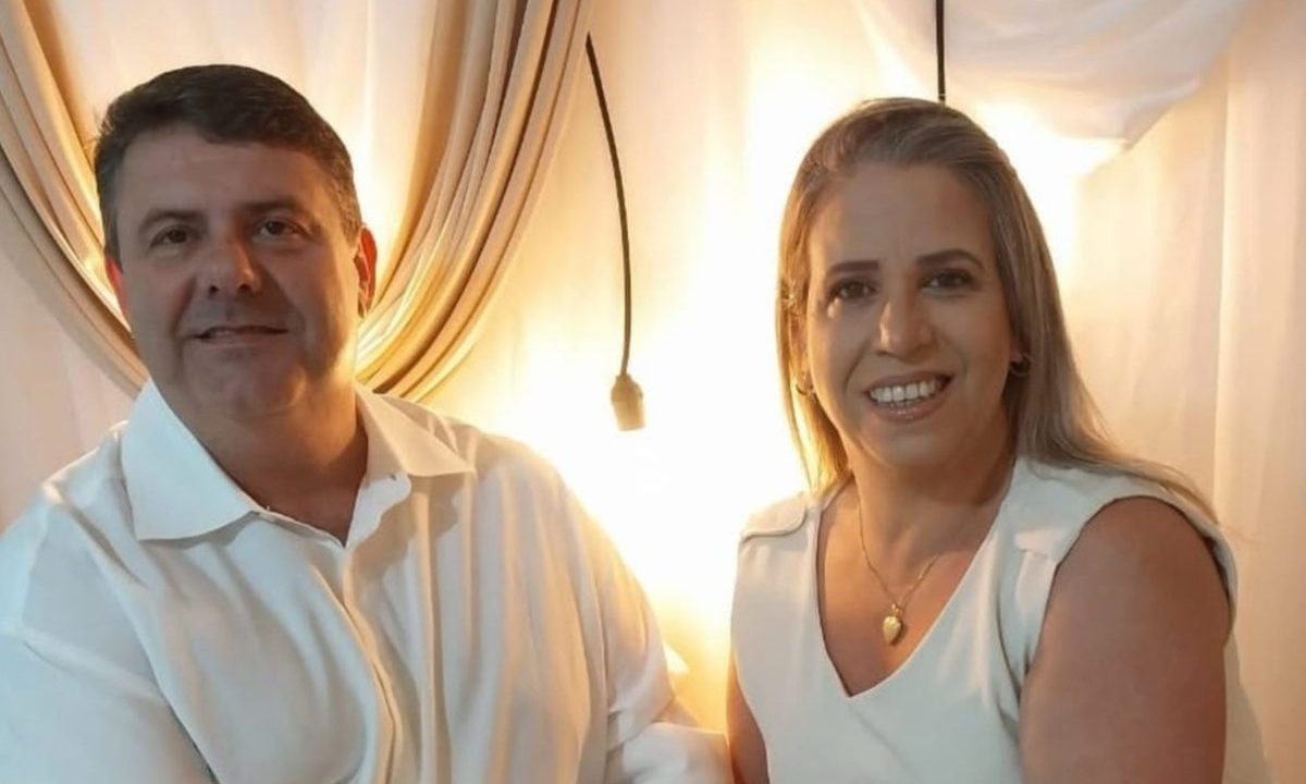 No registro aparece o casal de pastores, Cristiano Batista e Sandra Constante, vestidos de branco, juntos, sorrindo para a foto. Ao fundo, uma luz amarela e uma cortina branca