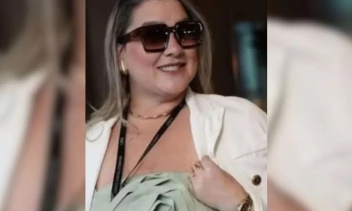Na foto aparece a patroa Carolina Sheila Ferreira dos Anjos, suspeita de agredir funcionária, usando óculos escuros e sorrindo para o registro, utilizando acessórios como brincos, um colar e um relógio, além de uma corda, em alusão a um crachá. Advogada deixou o caso dela.