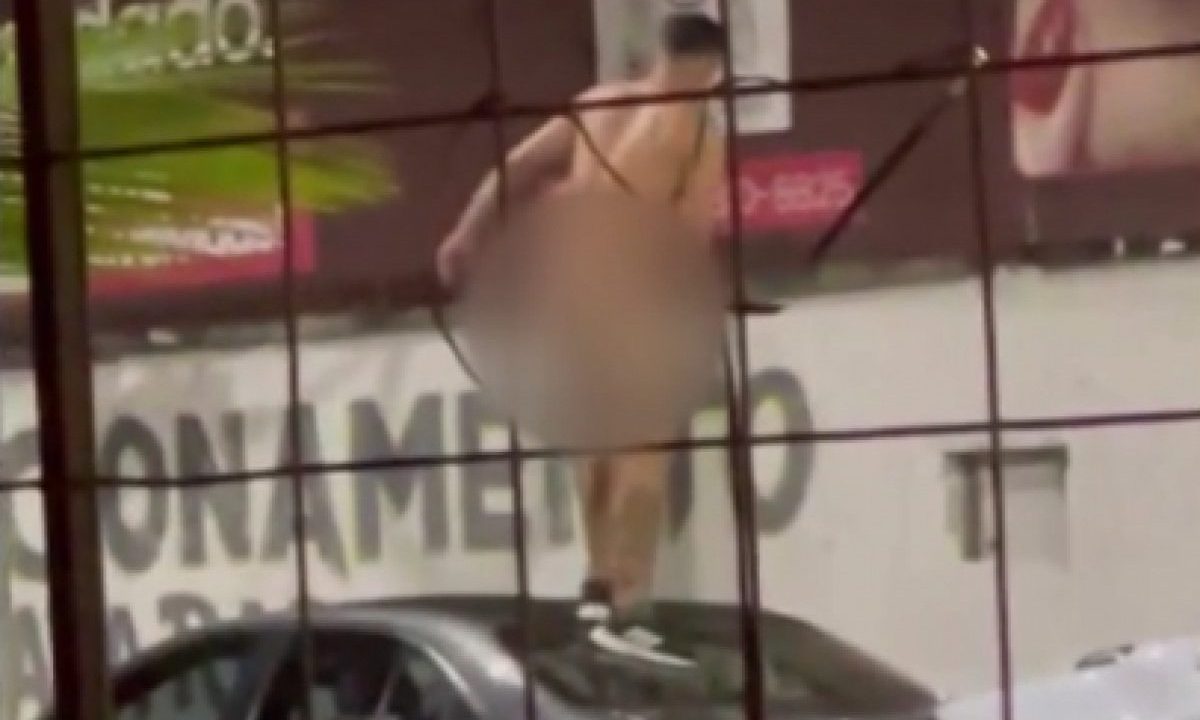 Imagem borrada mostra o homem pelado sobre o carro durante ataque de histeria após ser deixado no meio da rua