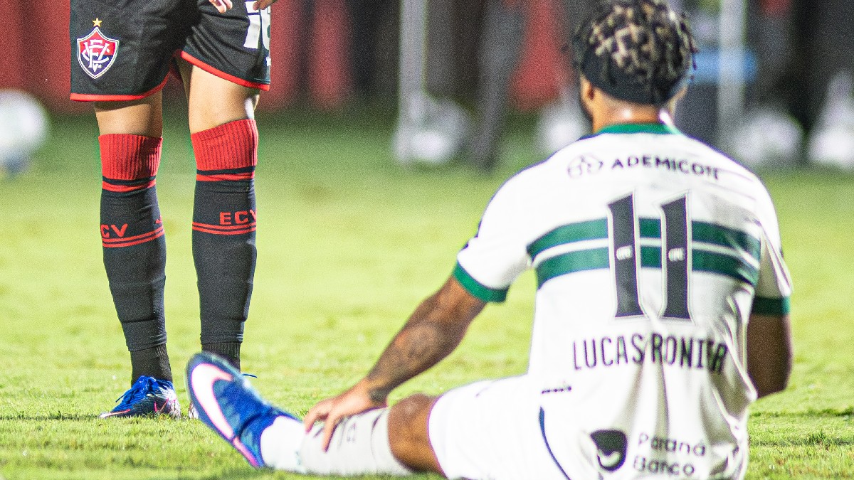 Lucas Ronier sentado no chão em Vitória x Coritiba, pelo Brasileirão