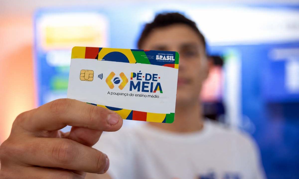 Foto de jovem segurando um cartão do Pé-de-Meia, programa que incentiva estudantes a manter frequência escolar.