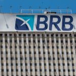 Fachada superior de edifício comercial com o letreiro azul e branco do BRB contra o céu azul, ilustrando as negociações envolvendo o Banco Regional de Brasília.