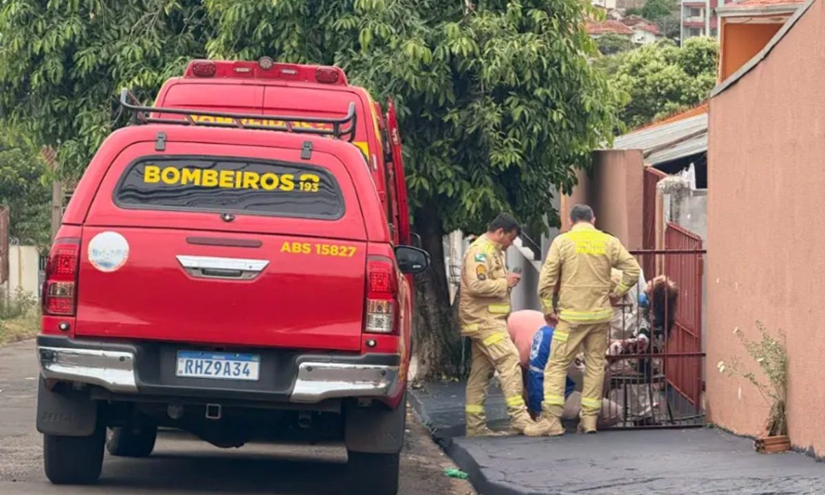 Na imagem aparece viaturas do Corpo de Bombeiros e agentes atendendo às vítima após o ataque, em uma calçada. Ao fundo, uma árvore e uma parede na cor salmão.
