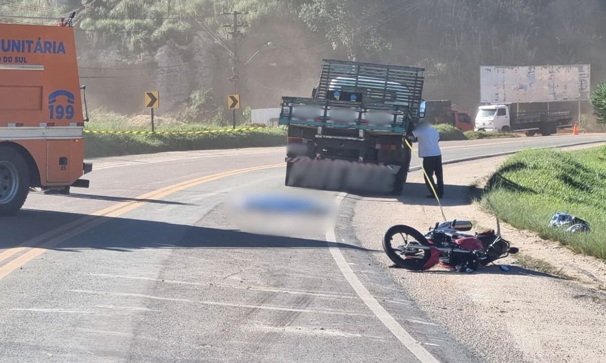 Motocicleta caída no asfalto perto de ambulância, de caminhão e do corpo da adolescente que morreu após acidente na Rodovia dos Minérios.