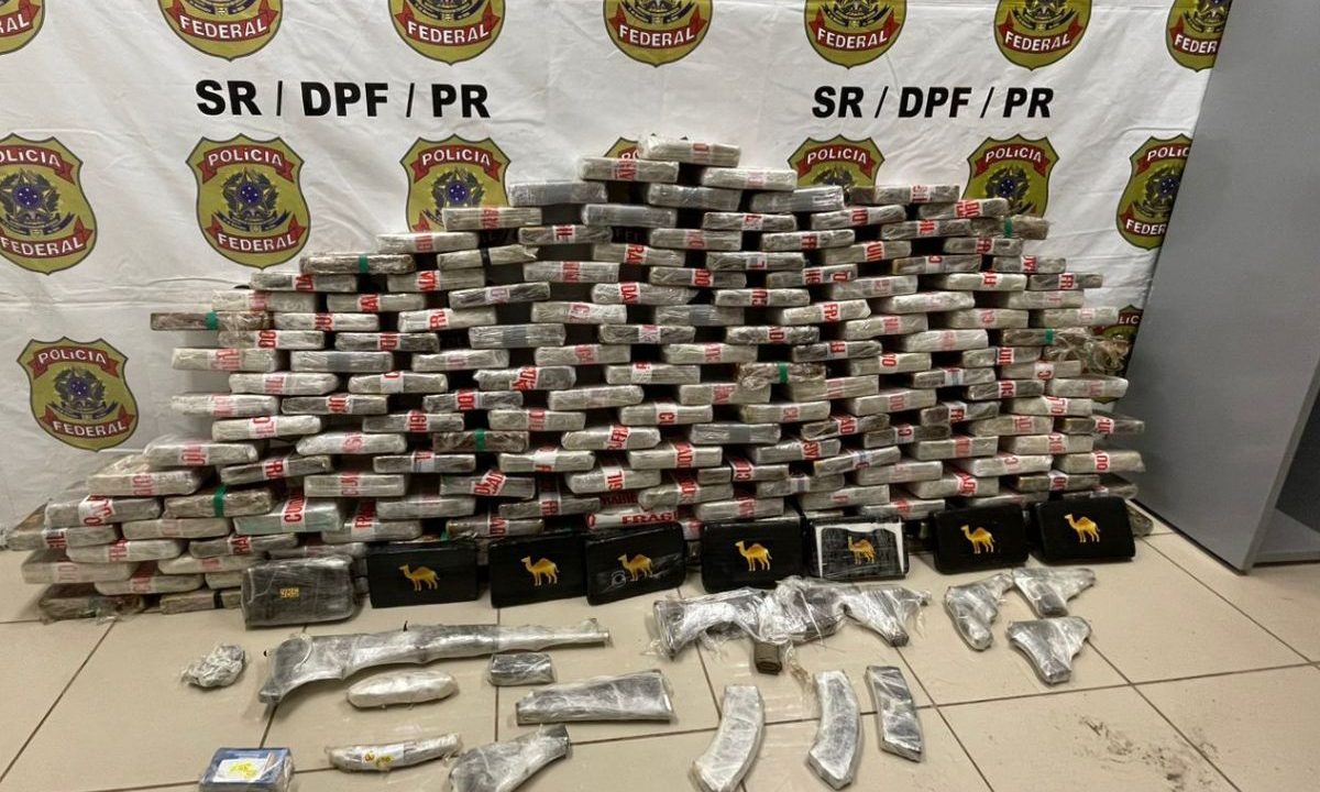 Tabletes de cocaína e arsenal de armas apreendidos pela Polícia Federal expostos em delegacia.