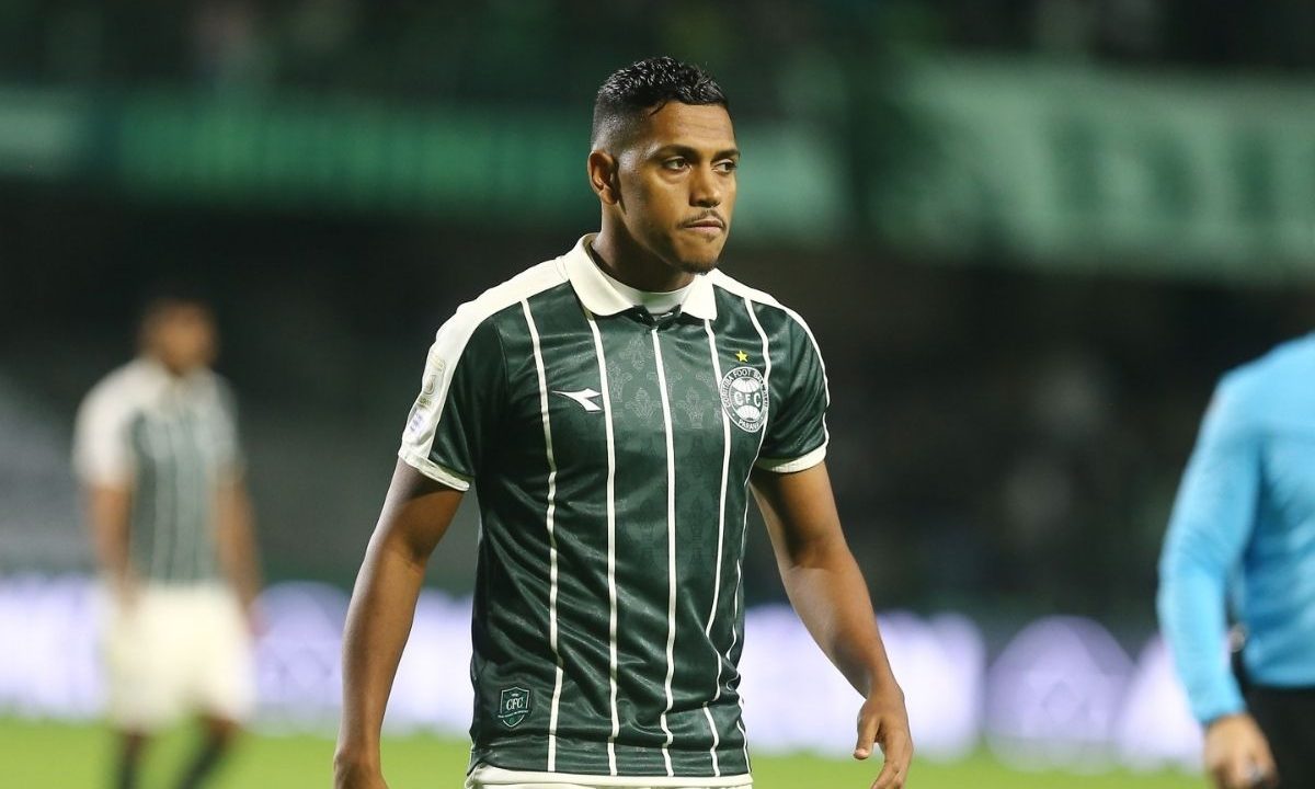 Pedro Rocha caminha pelo gramado usando a camisa do Coritiba durante partida noturna no Couto Pereira.