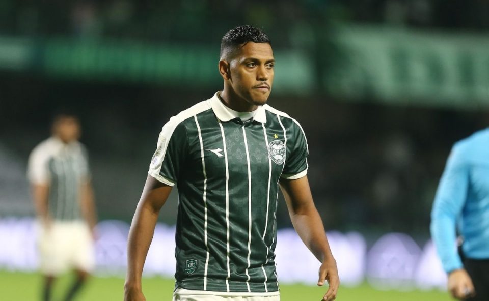 Pedro Rocha caminha pelo gramado usando a camisa do Coritiba durante partida noturna no Couto Pereira.