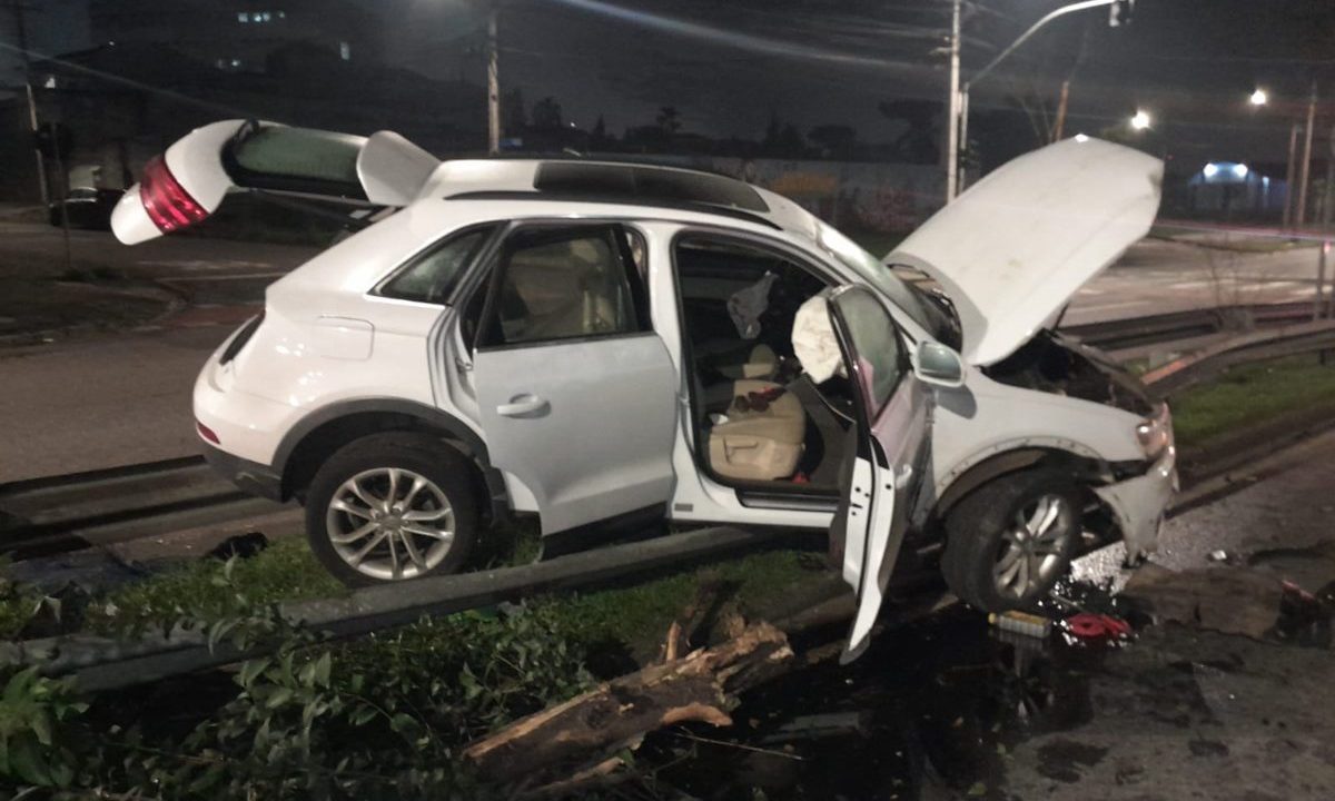 Na imagem aparece o veículo da marca Audi, atravessado entre uma pista e outra, após subir um guard-rail, após o motorista perder o controle da direção, durante a madrugada