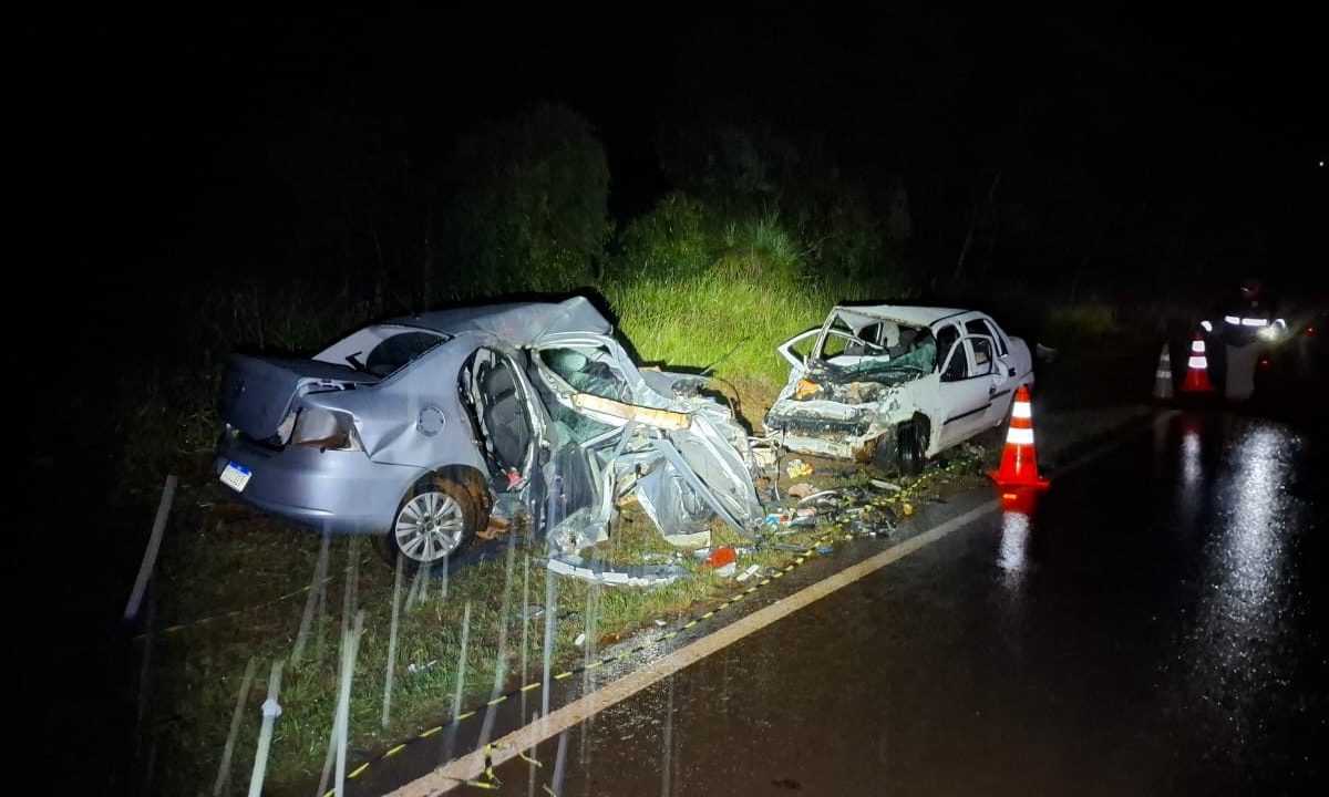 Foto tirada durante a noite mostra os dois carros envolvidos na grave batida que matou três mulheres e deixou outras três pessoas gravemente feridas na PR-473; os dois veículos estão totalmente destruídos. A pista está molhada