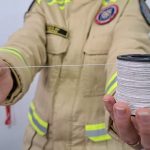 Bombeira segura carretel de linha usado em pipas durante alerta sobre os perigos do cerol e de linhas cortantes no Paraná.