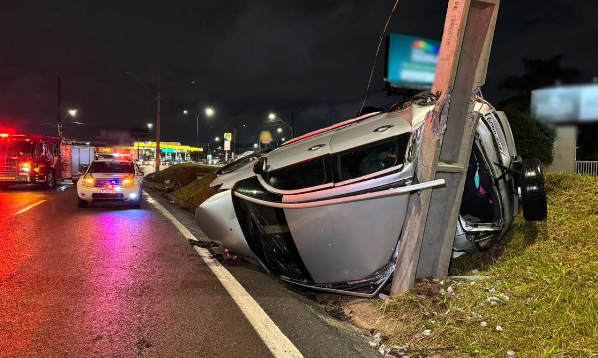 Carro capotado e destruído após bater em poste na Avenida das Torres, em São José dos Pinhais, durante a noite chuvosa.