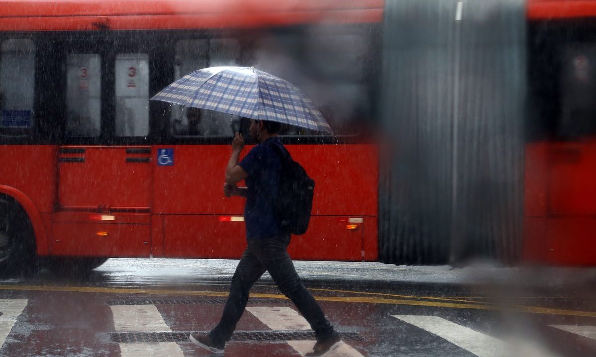 pessoa andando na chuva para ilustrar a chegada do ciclone que aumenta o risco de tempestades no paraná