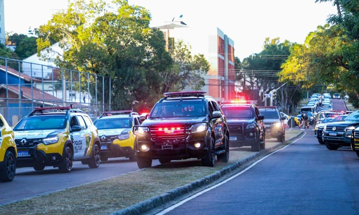 Imagem representa o levantamento que mostra que uma cidade do Paraná ficou entre as 30 com mais homicídio no Brasil. Há diversas viaturas da Polícia Militar na rua.