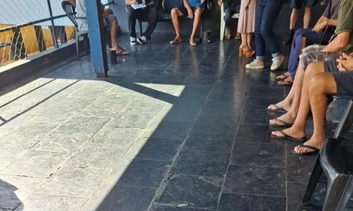 Foto mostra pacientes de torturados em clínica de reabilitação sentados em um banco na área externa do estabelecimento, sem que os rostos sejam mostrados.