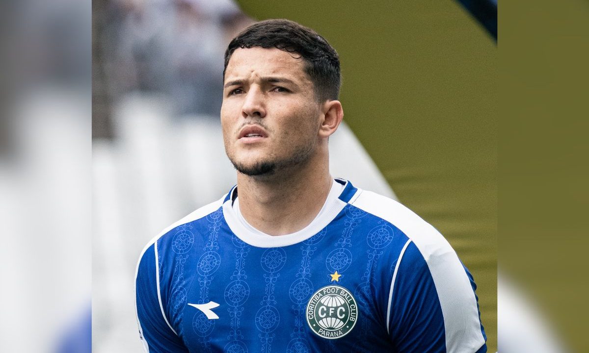 Pedro Rangel aparece em primeiro plano usando uniforme azul do Coritiba antes de uma partida. O goleiro olha para frente em expressão concentrada.