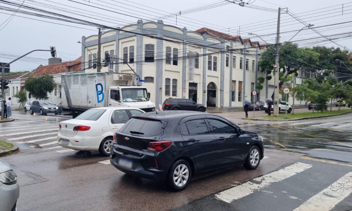 Carros passam por cruzamento com semáforos apagados no bairro Rebouças, em Curitiba, após ventania causar falta de luz.