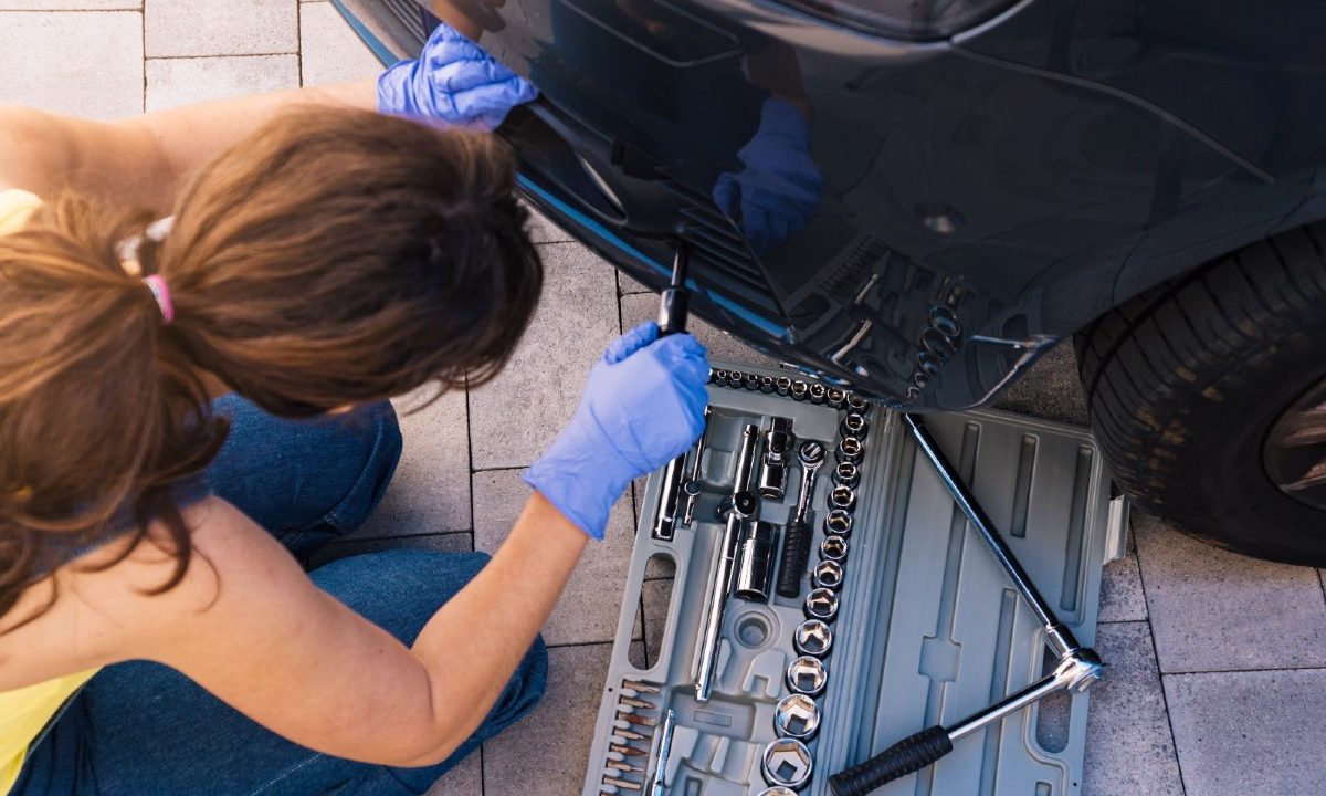 na imagem, uma mulher fazendo reparos mecânicos em um carro