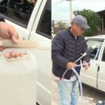 Entregador mostra galão e mangueira usados em teste após bomba registrar mais de 62 litros abastecidos em um Fiat Uno e denuncia cobrança irregular em posto em Curitiba.