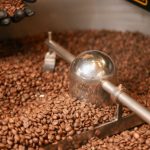 Dia Nacional do Café: grãos de café torrados espalhados sobre superfície de madeira.