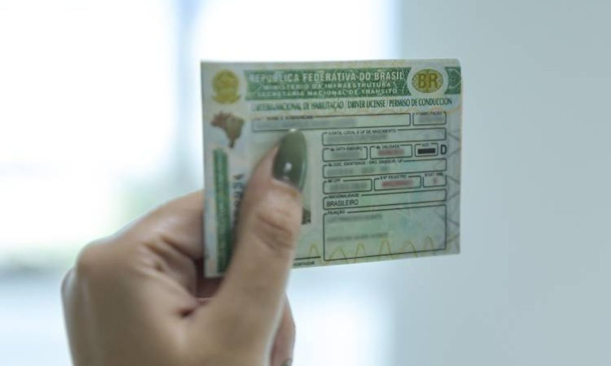 Foto ilustrativa para a notícia sobre como funciona o exame toxicológico para quem vai tirar a primeira CNH. Foto mostra uma mão com unha comprida, pintada de verde, segurando uma CNH.
