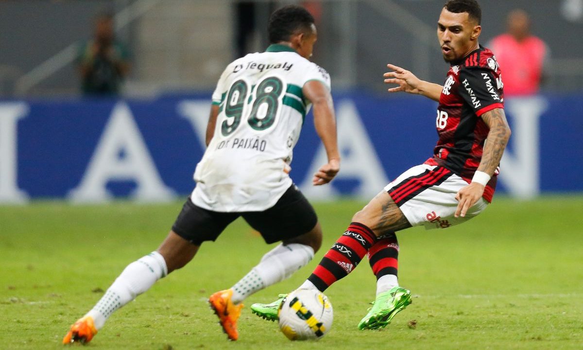 Jogador do Coritiba disputa a bola com atleta do Flamengo durante partida no Maracanã. Os dois aparecem em ação no gramado em lance do confronto pelo Campeonato Brasileiro.