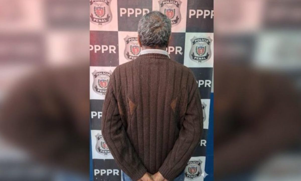 Na imagem aparece o idoso posando de costas ,algemado, em uma delegacia da Polícia Civil